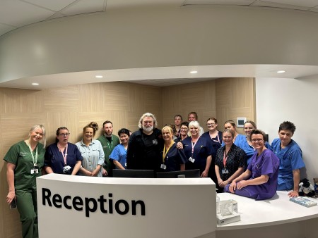 A group staff standing together smiling with Si King at the reception of the oncology unit