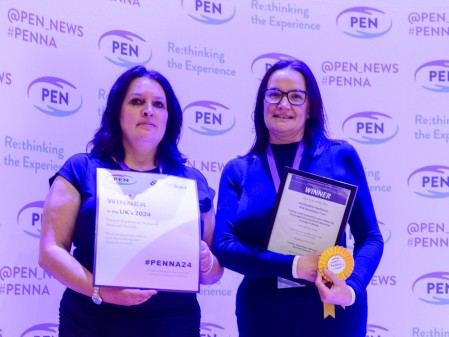 Two people holding awards and certificates.