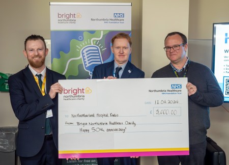 Three men holding a large cheque