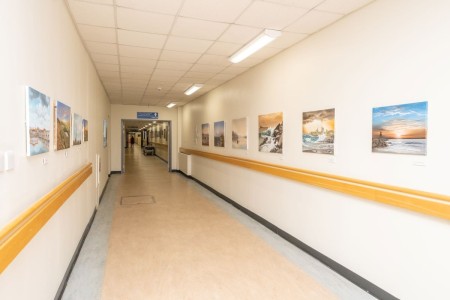 A corridor in a hospital. The walls have lots of artwork on them.