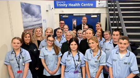 Group of students standing outside double doors at the opening of a healthcare suite 