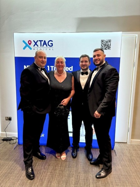 4 men and a women in black tie dress standing together smiling 