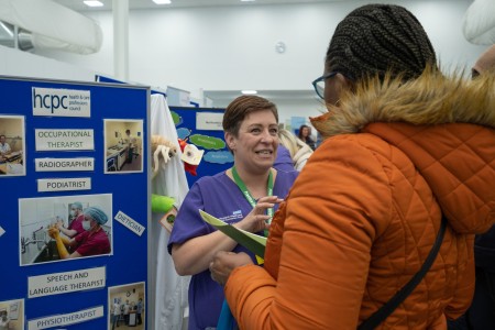 A lady engaging conversation with another lady who has her back faced towards the camera at the Find Your Future Careers event in 2023 